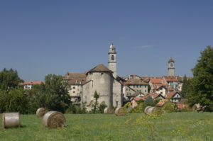 Prato e fieno raccolto, chiesa e casette